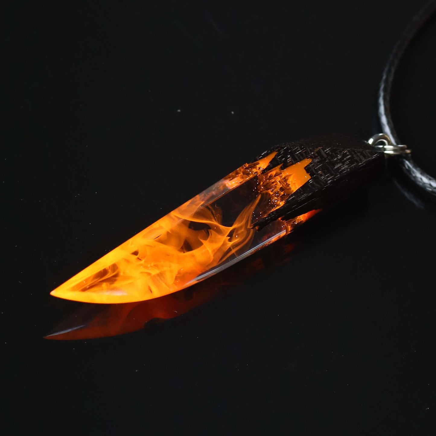 Wood resin necklace with orange fire design inside a fang-shaped pendant, handmade flame jewelry on black cord