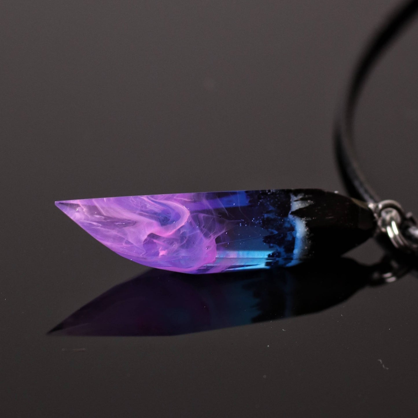 Wood resin necklace with purple and blue nebula design inside a faceted fang-shaped crystal pendant, handmade galaxy jewelry