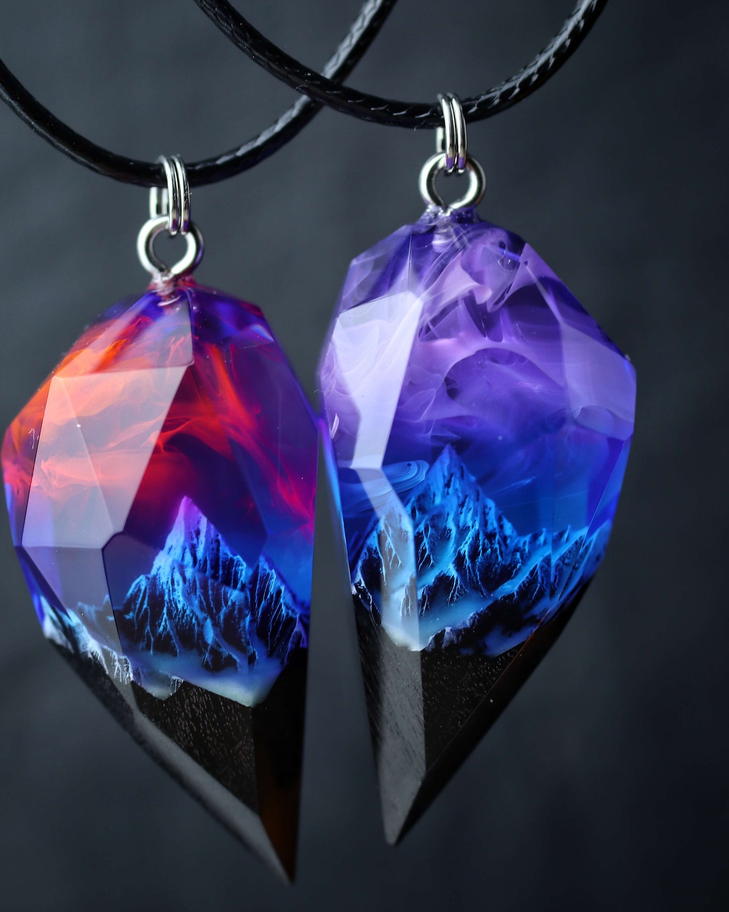Matching couple necklace set, two faceted crystal pendants forming a heart, handmade wood resin jewelry with purple nebula and mountains, held in hand