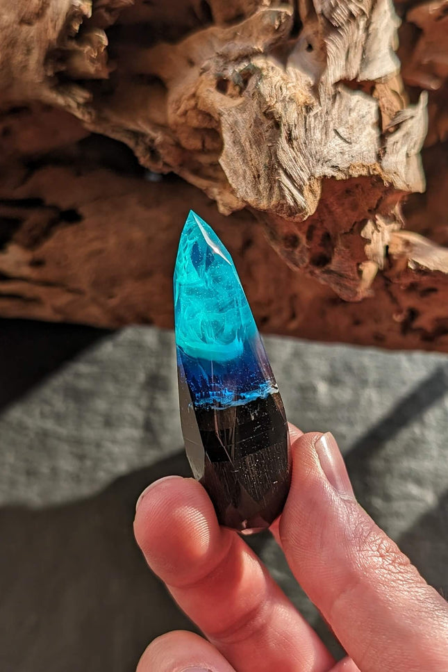 Hand holding handmade wood resin USB stick with northern lights effect