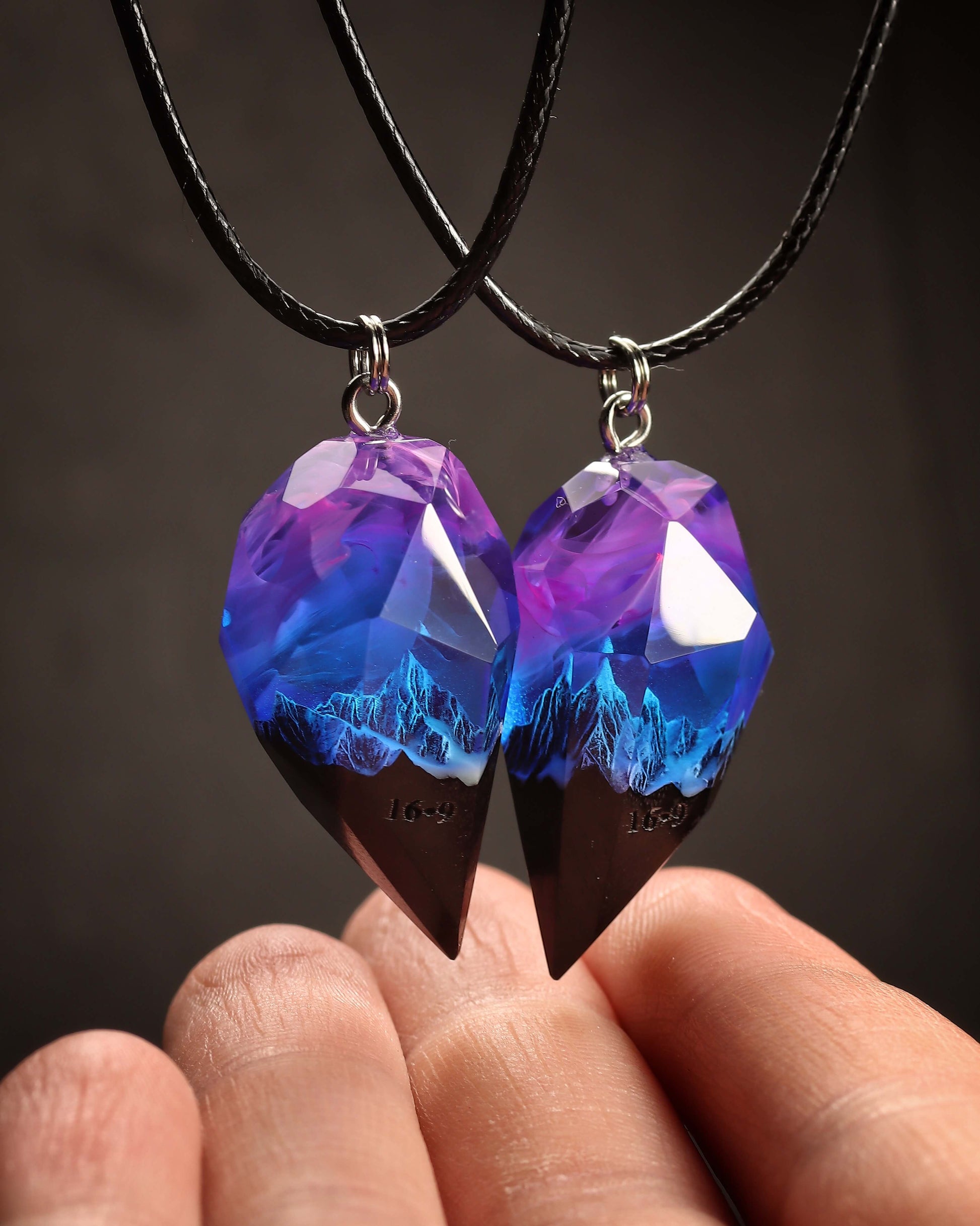Hand holding resin and wood couple heart pendants with galaxy design