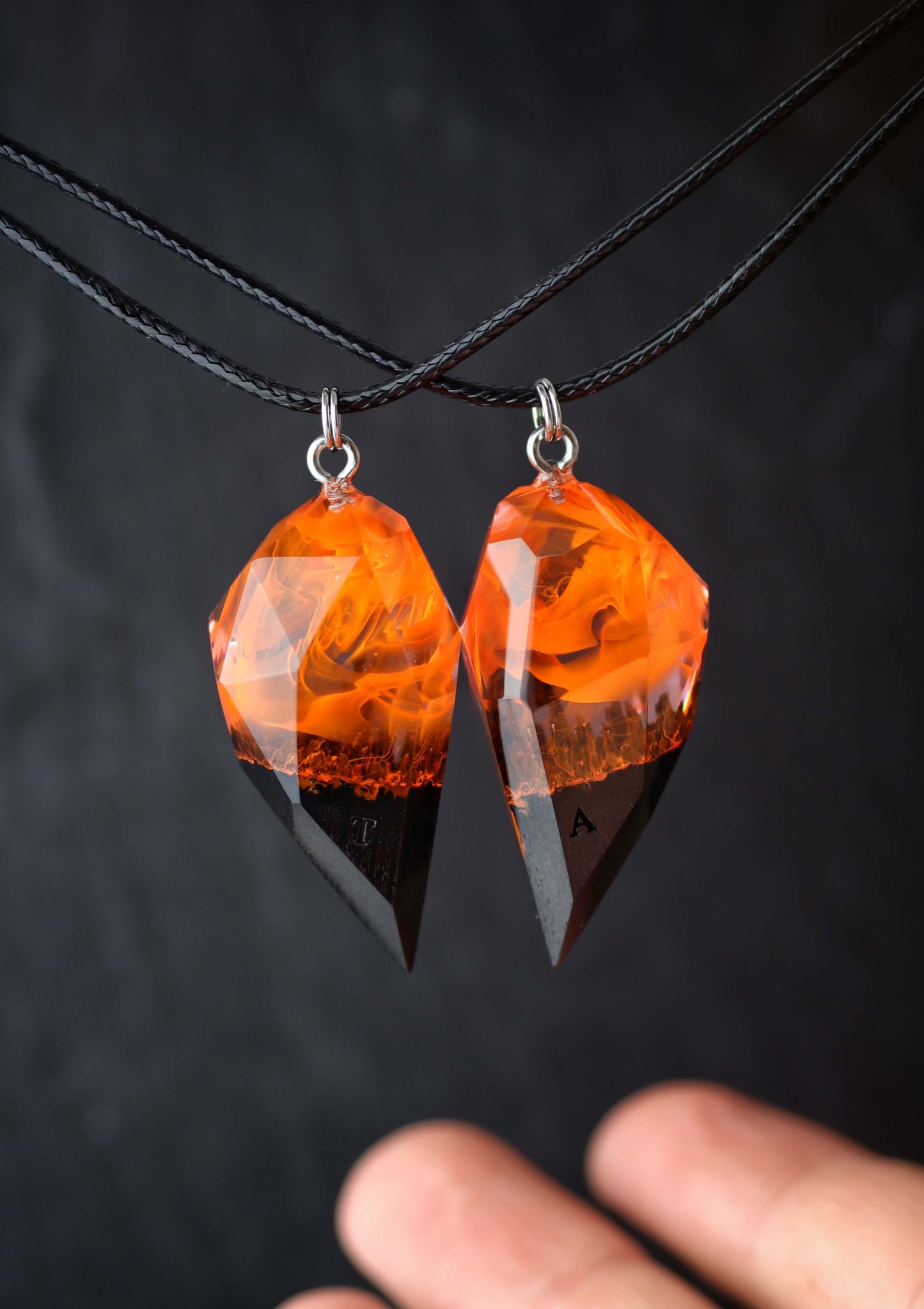 Hand holding handmade resin wood couple pendants with fire design