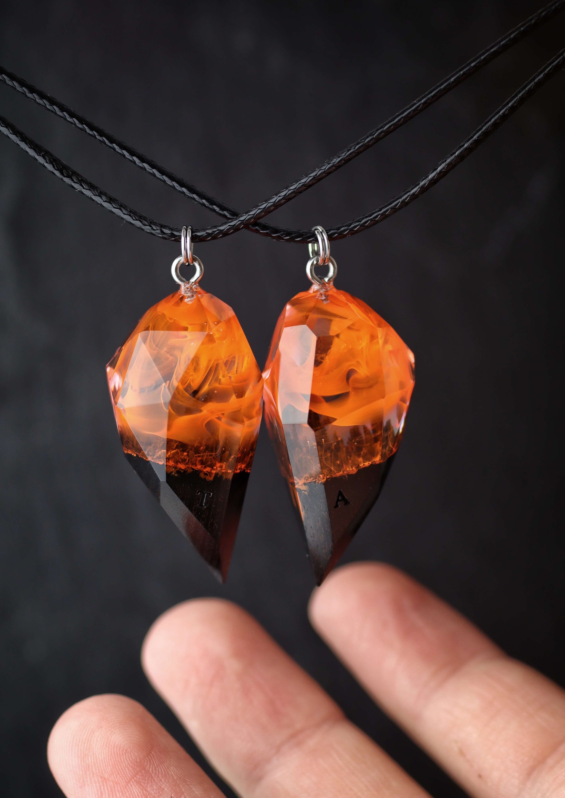 Hand holding handmade resin wood couple pendants with fire design