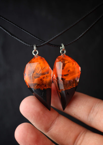 Hand holding handmade resin wood couple pendants with fire design