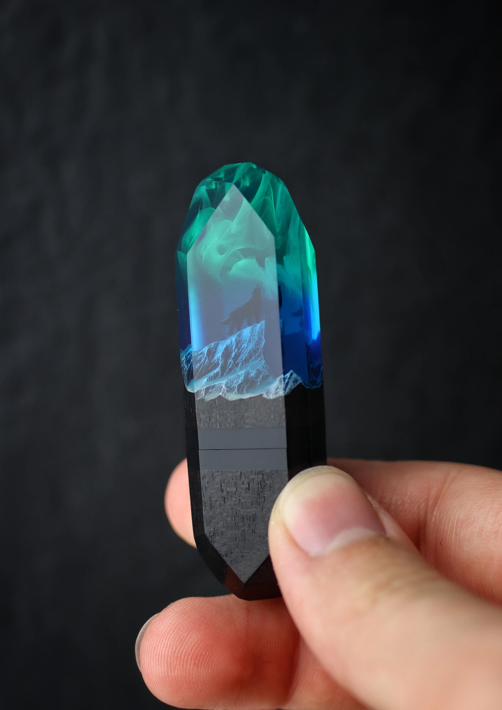 Hand holding handmade resin wood USB stick with wolf inside