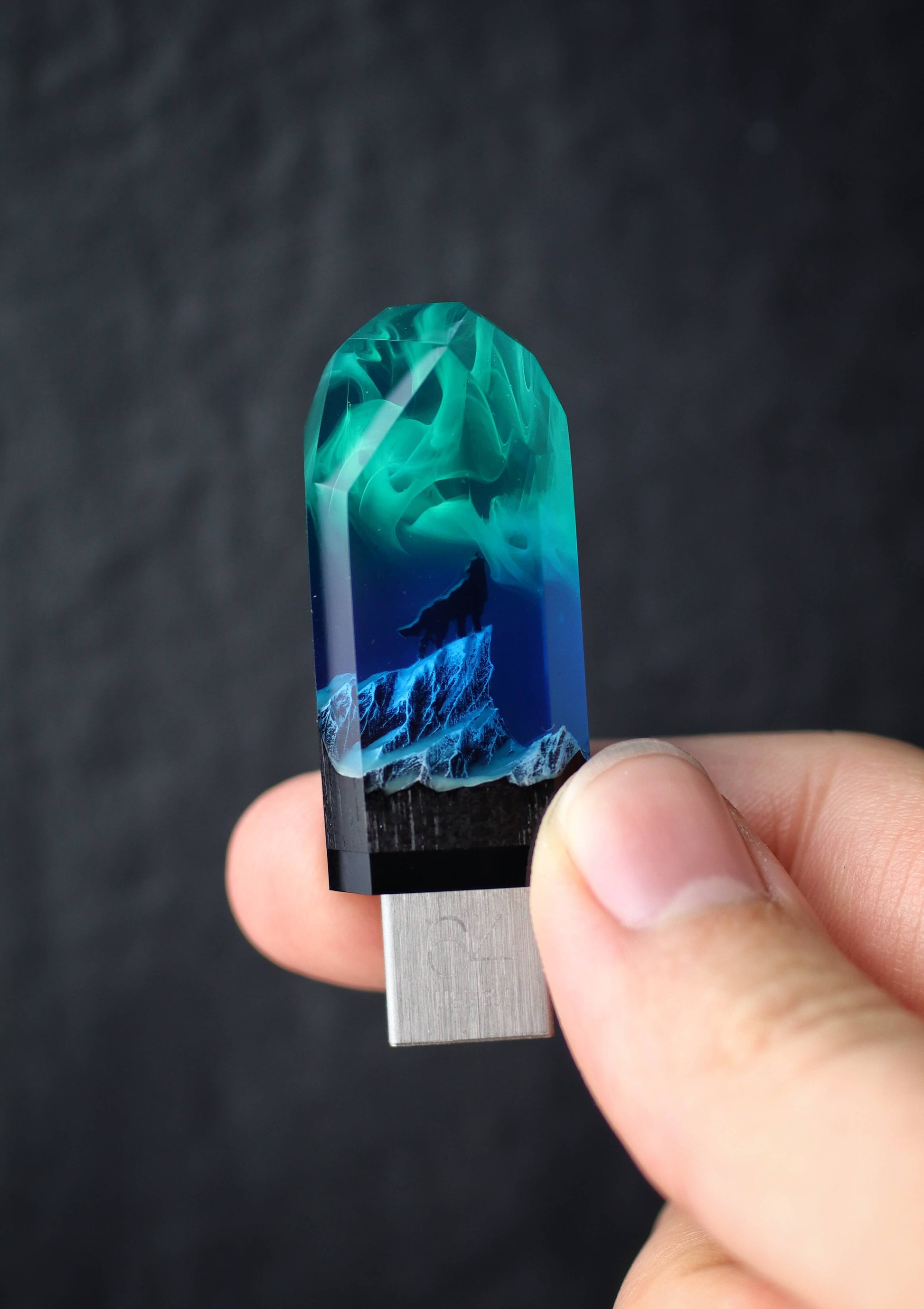 Hand holding a USB drive with a blue and green design against a dark background