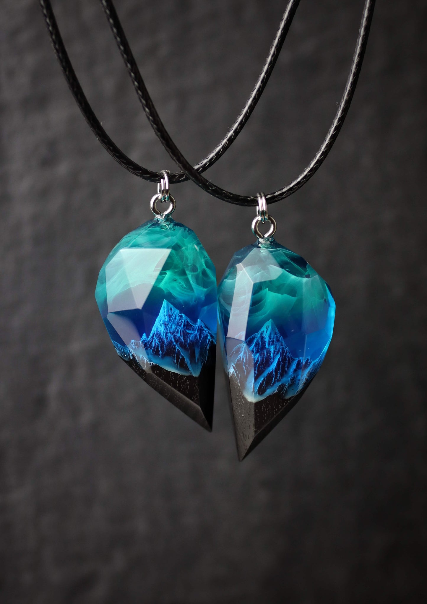 Pair of resin wood heart pendants glowing in blue northern lights style